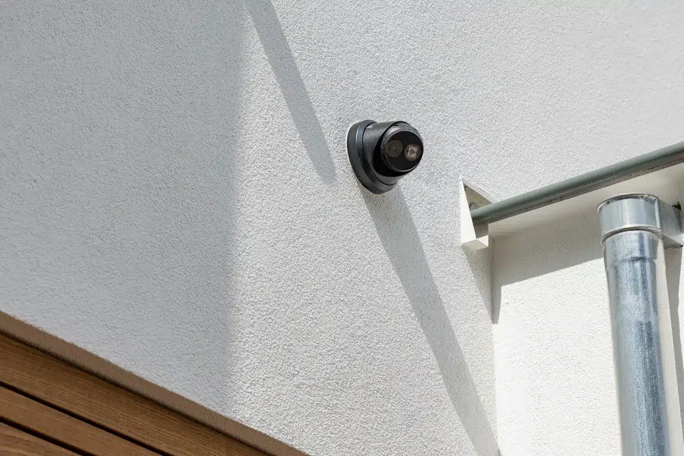 Zwarte ronde beveiligingscamera gemonteerd op een witte buitenmuur.