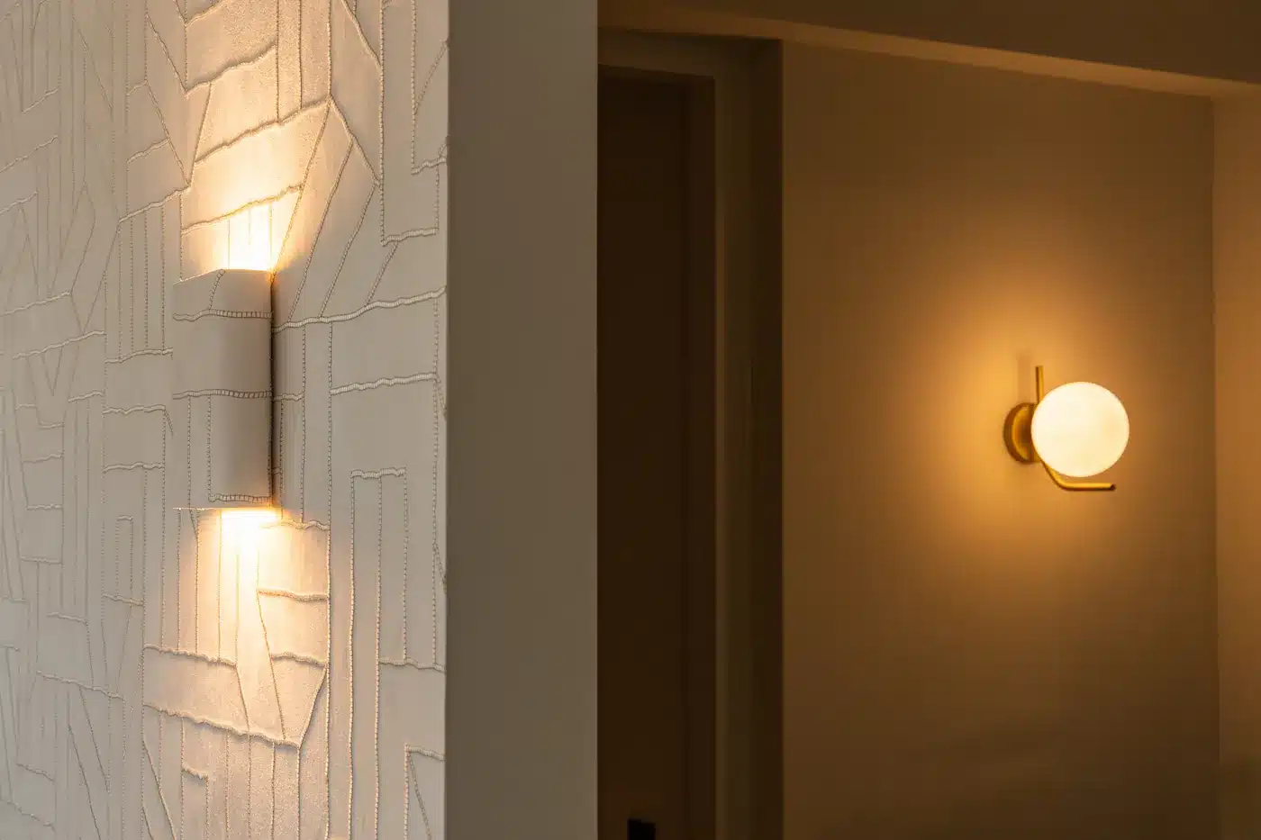 Luxe wandlamp op een witte muur met een modern reliëfpatroon.